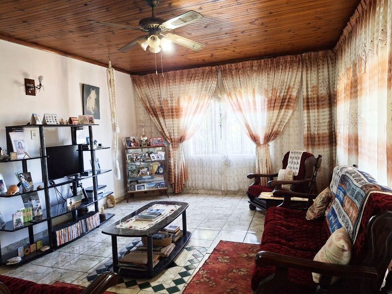 A living room featuring a timber-clad ceiling with a central fan and ceramic tiled flooring.