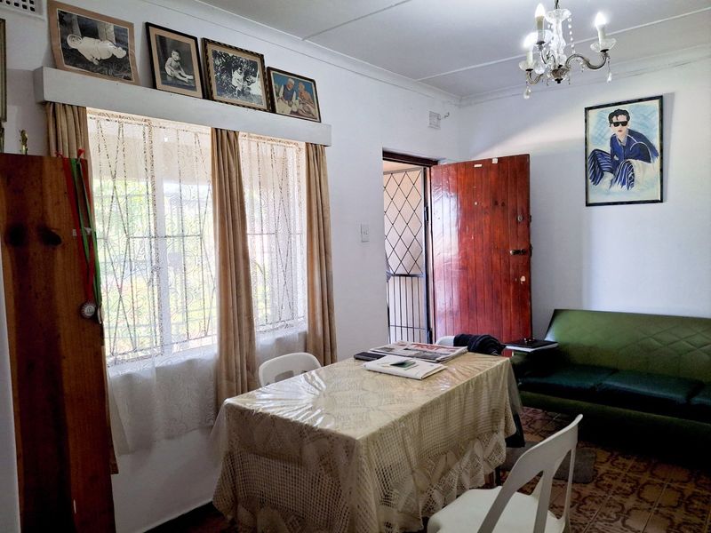 A living area featuring tiled flooring, a chandelier, and a security gate, offering a functional space with potential for modern updates.