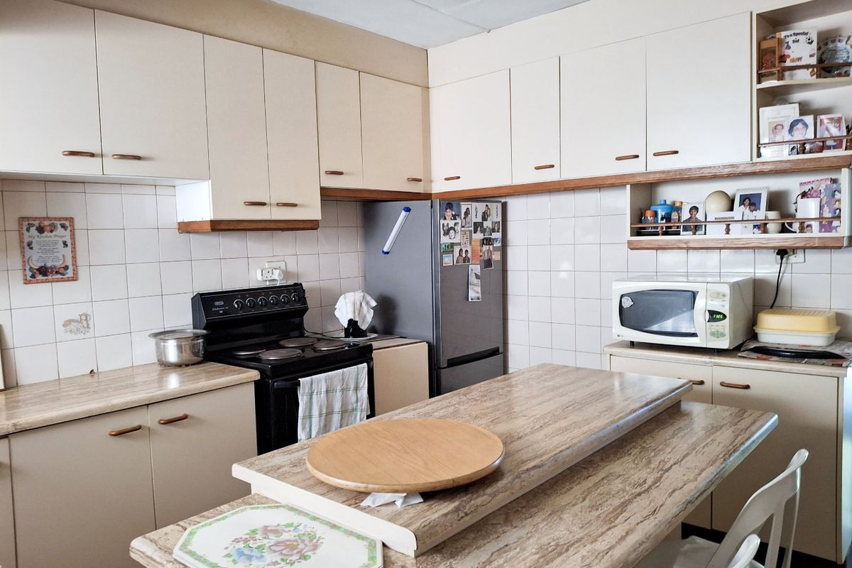 A functional kitchen featuring laminate countertops, tiled backsplash, and ample built-in cabinetry, offering a practical layout for daily meal preparation.