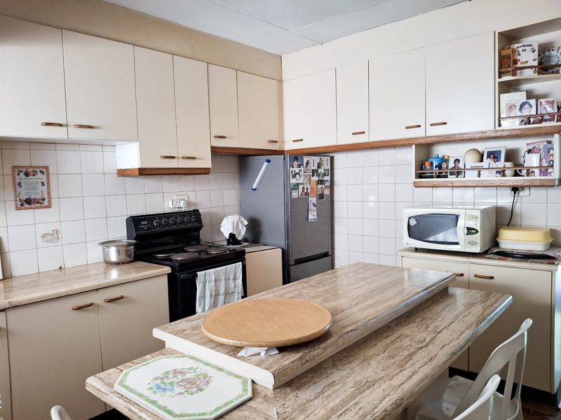 A functional kitchen featuring laminate countertops, tiled backsplash, and ample built-in cabinetry, offering a practical layout for daily meal preparation.