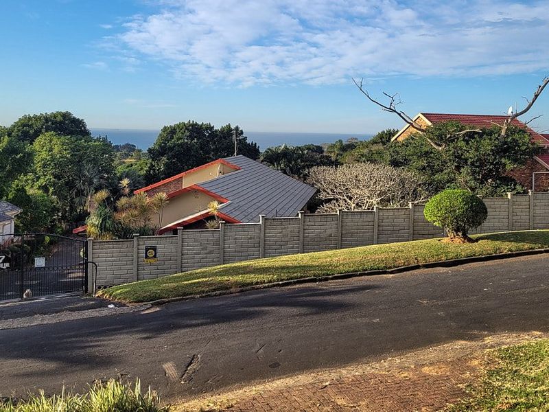 Street view of the property entrance featuring a secure boundary wall, gated access, and a view of the surrounding residential area.