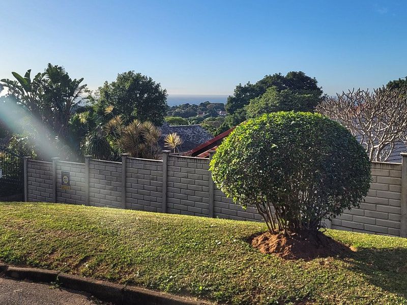 Street view of the property frontage featuring a well-maintained verge, precast concrete boundary wall, and secure gated entrance.