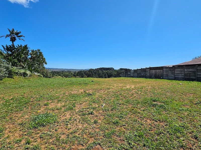 A spacious, open garden area featuring a precast concrete boundary wall and expansive views of the surrounding landscape.