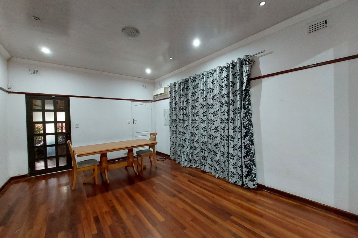 Spacious living area featuring polished hardwood flooring, recessed downlighting, and an integrated air conditioning unit, offering a versatile space for relaxation.