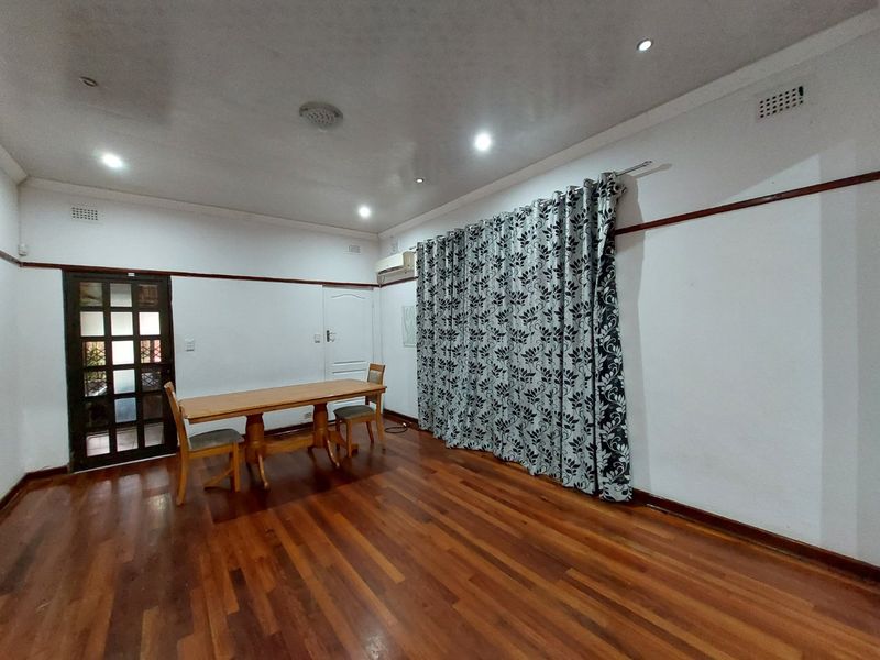 Spacious living area featuring polished hardwood flooring, recessed downlighting, and an integrated air conditioning unit, offering a versatile space for relaxation.
