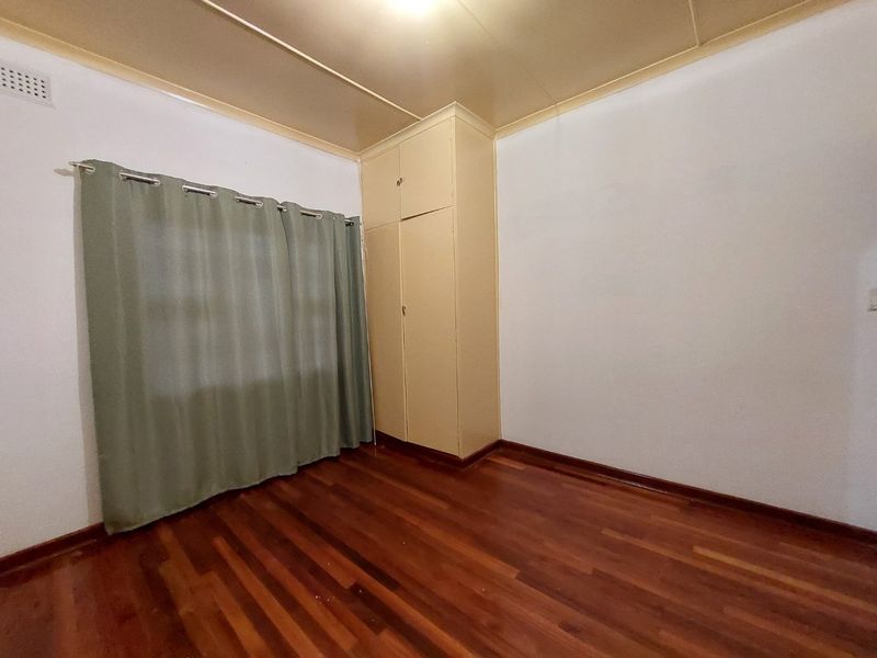 A vacant bedroom featuring polished hardwood flooring, a built-in wardrobe, and neutral wall finishes, offering a clean canvas for personalization.