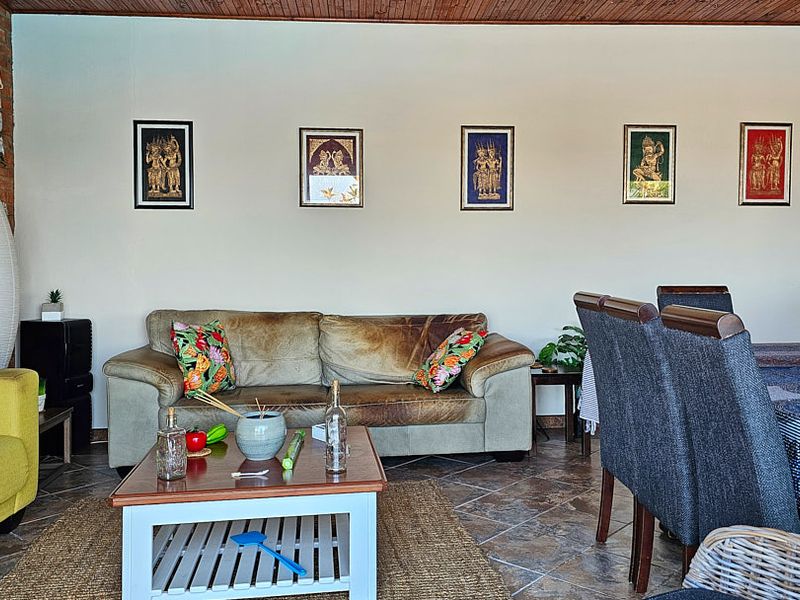 Open plan living and dining area featuring exposed brick wall detailing, timber ceiling, and tiled flooring.