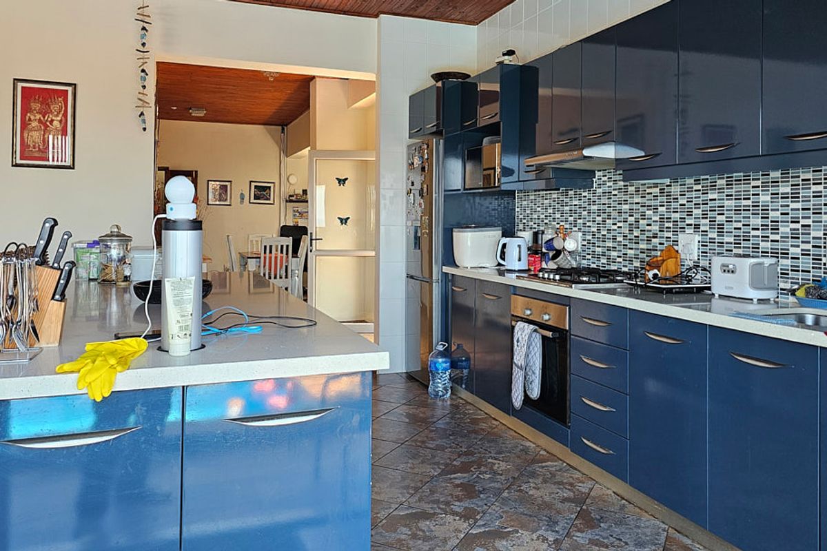 Modern kitchen featuring dark blue cabinetry, stone countertops, a mosaic tile backsplash, and a functional kitchen island, providing ample workspace and storage.