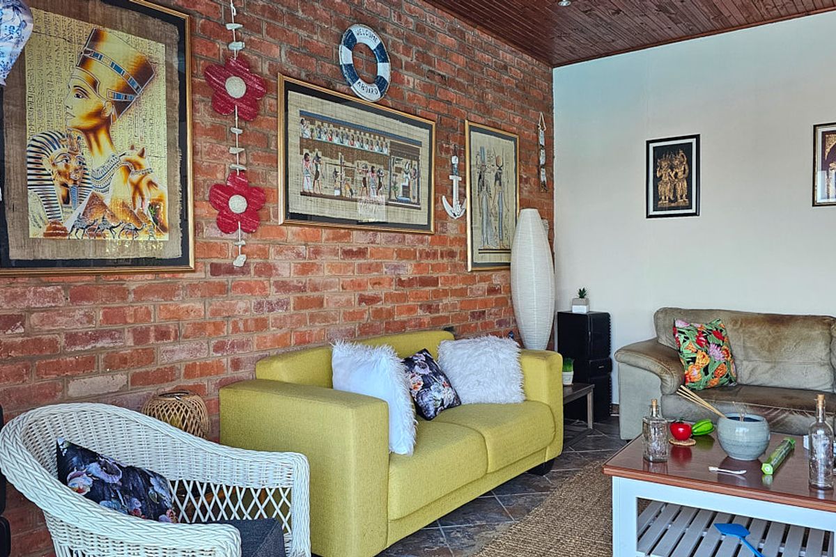 A living room featuring an exposed brick feature wall, timber-paneled ceiling, and tiled flooring, offering a rustic and textured aesthetic.
