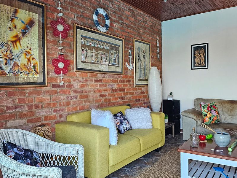 A living room featuring an exposed brick feature wall, timber-paneled ceiling, and tiled flooring, offering a rustic and textured aesthetic.