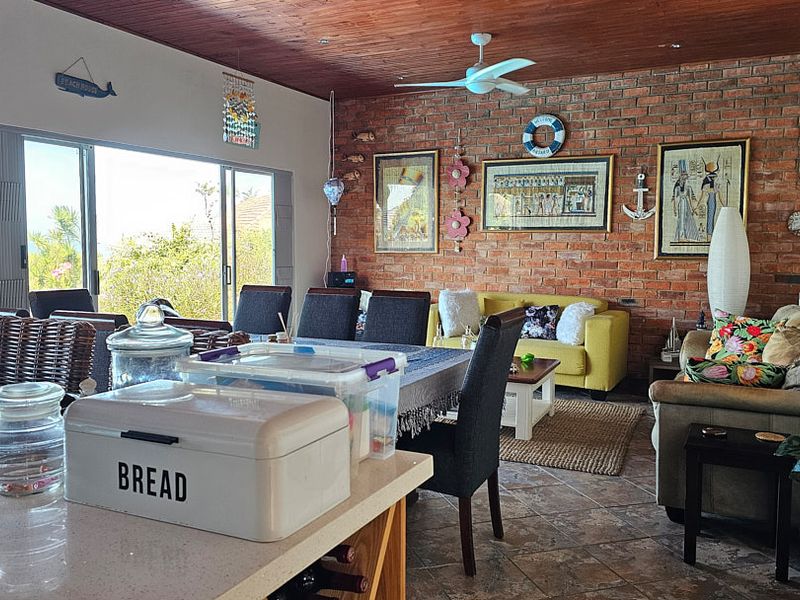 Spacious open-plan living and dining area featuring an exposed brick feature wall, timber ceiling, and large sliding doors leading to the outdoors.