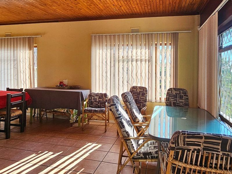 Spacious dining area featuring a warm timber ceiling, tiled flooring, and large windows with vertical blinds and security gates.