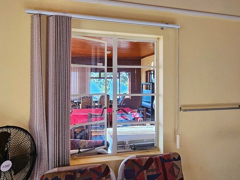 Interior view of a living area featuring a steel-framed window looking out onto an adjacent patio space.