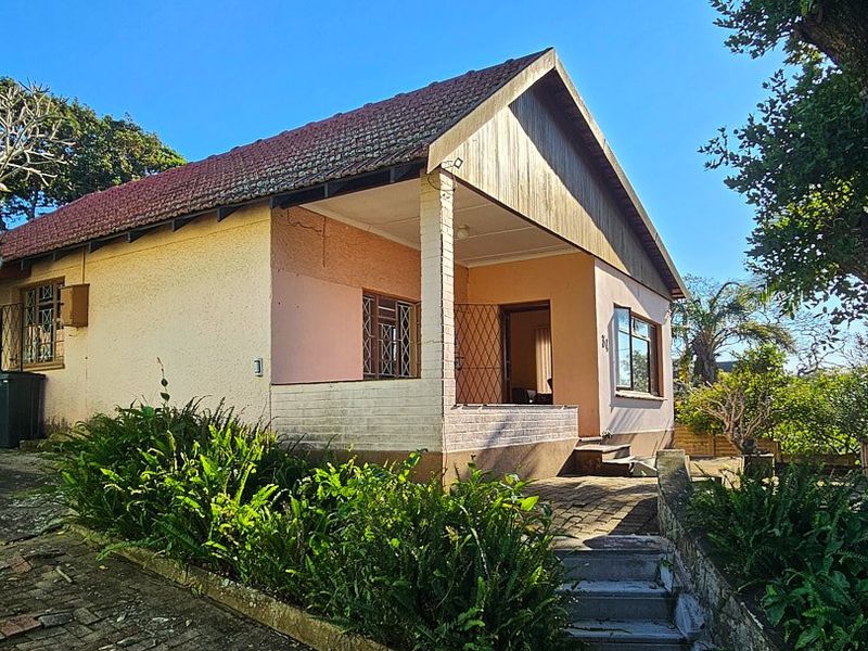 Front view of a single-story house featuring a covered porch, brick and plaster exterior, and paved entrance steps.