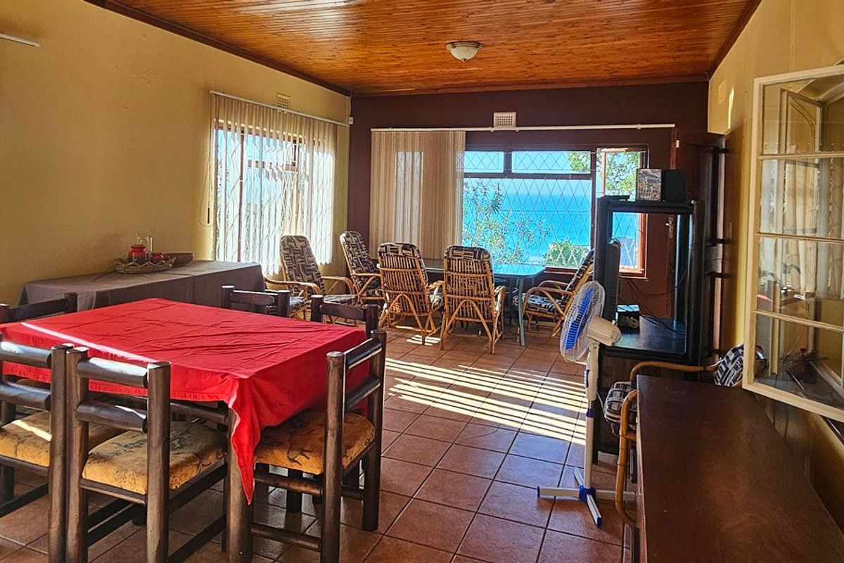 Spacious living area featuring timber ceilings, tiled flooring, and large windows with security bars, offering natural light and views.