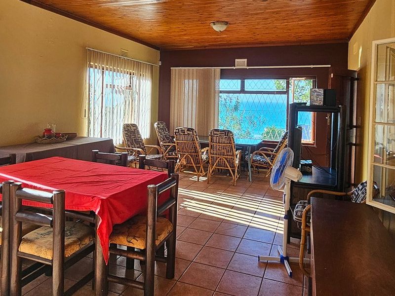 Spacious living area featuring timber ceilings, tiled flooring, and large windows with security bars, offering natural light and views.