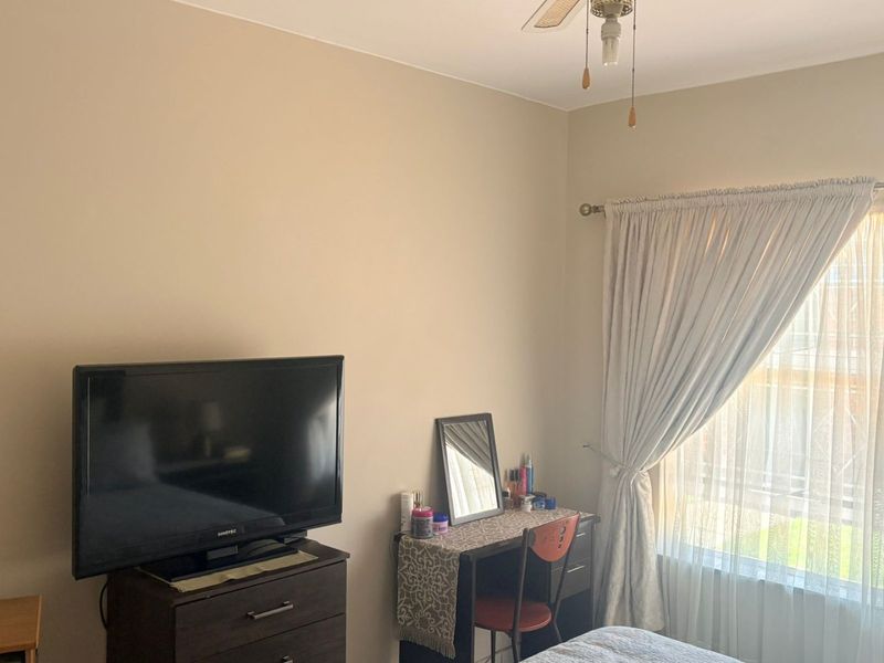 A bedroom featuring a ceiling fan and natural light through a window with curtains.