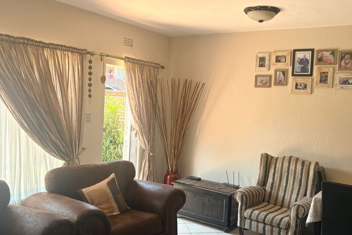 A comfortable living room featuring tiled flooring and a sliding glass door that provides natural light and access to the outdoor area.
