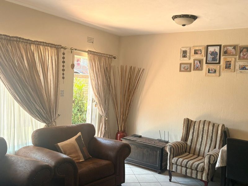 A comfortable living room featuring tiled flooring and a sliding glass door that provides natural light and access to the outdoor area.