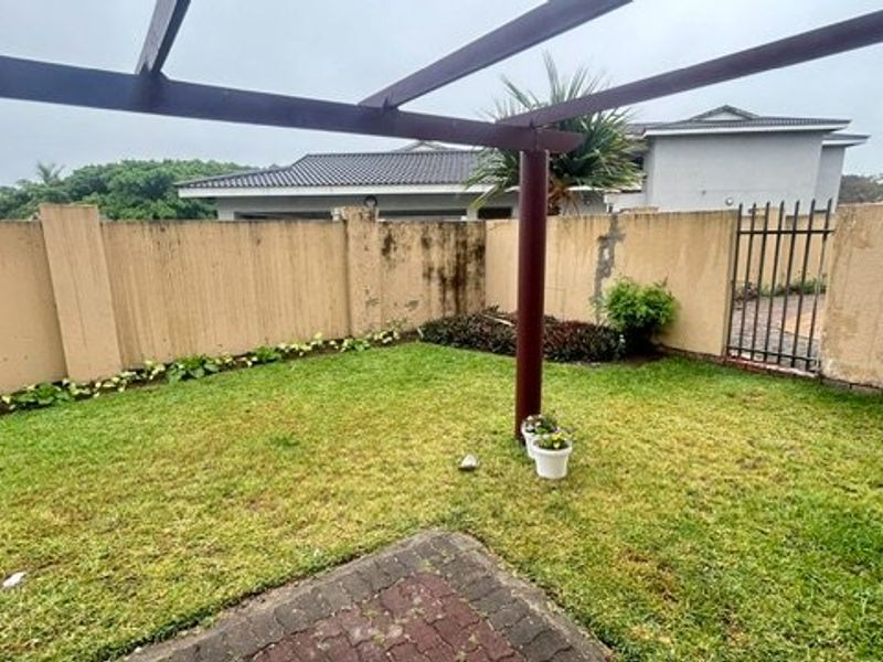 A private garden area featuring a pergola structure, paved section, and perimeter boundary walls requiring maintenance.
