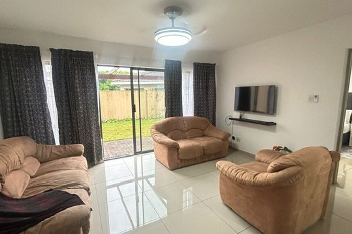 A living room featuring tiled flooring, a ceiling fan, and a sliding glass door providing access to the outdoor area.
