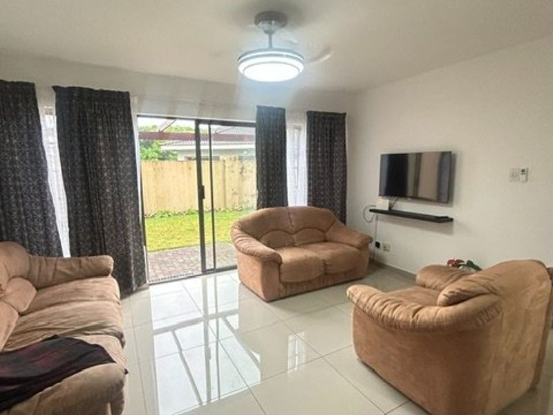 A living room featuring tiled flooring, a ceiling fan, and a sliding glass door providing access to the outdoor area.