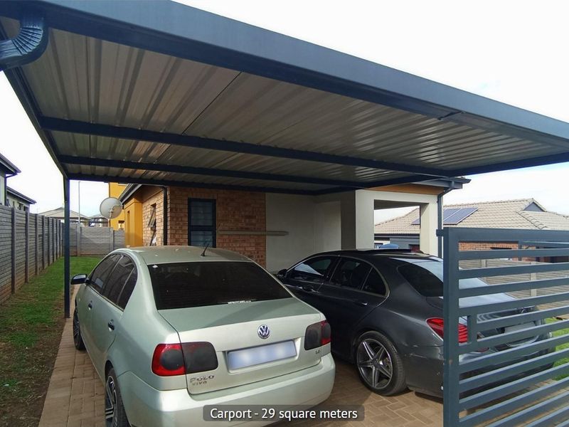 A spacious 29 square meter metal carport providing covered parking, featuring a paved driveway and secure gated access.