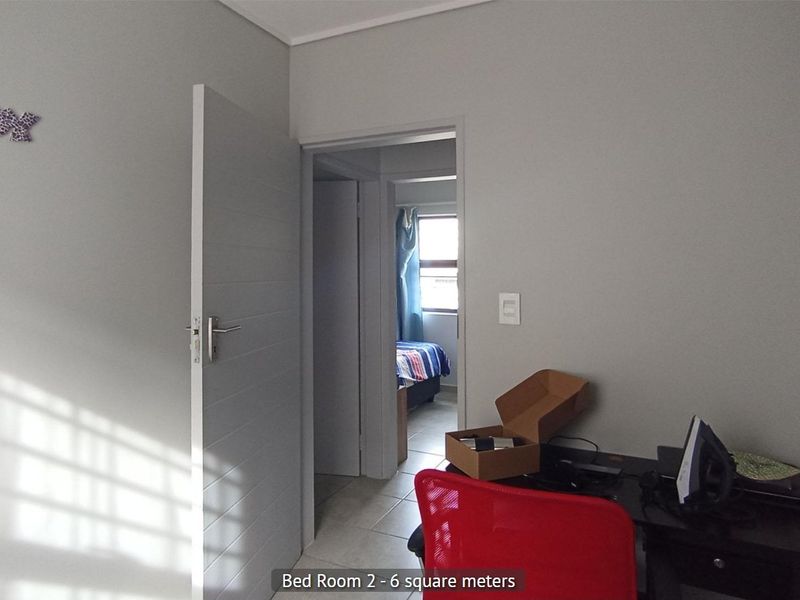 A view of a bedroom featuring tiled flooring and an internal door, with a glimpse into the adjacent room.