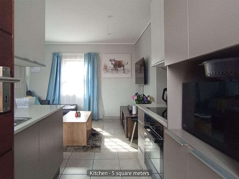 Open-plan kitchen and living area featuring modern cabinetry, integrated appliances, and tiled flooring, creating a functional and cohesive living space.