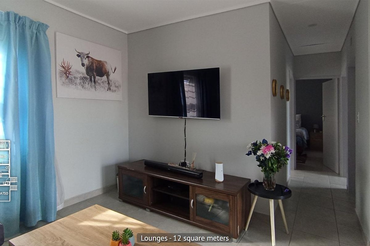 A compact living room featuring neutral wall tones, tiled flooring, and a wall-mounted television setup, providing a functional and well-maintained space.