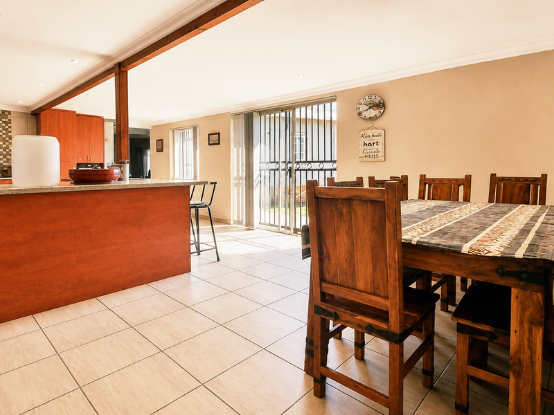 Spacious open-plan kitchen and dining area featuring tiled floors, a large kitchen island with granite countertops, and direct access to the outdoors via sliding doors.