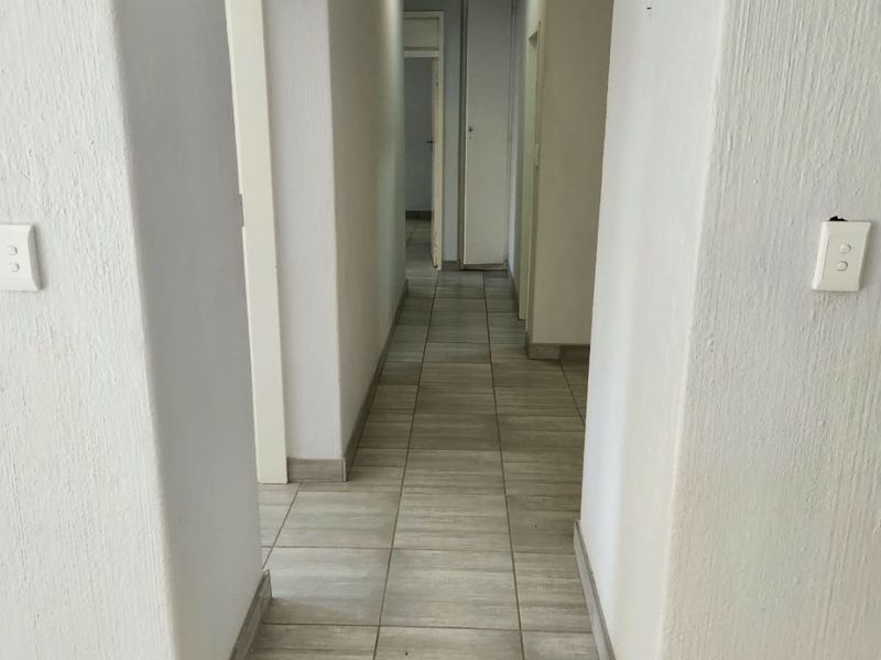 A clean, neutral hallway featuring tiled flooring and access to multiple rooms, providing a functional transition space within the townhouse.