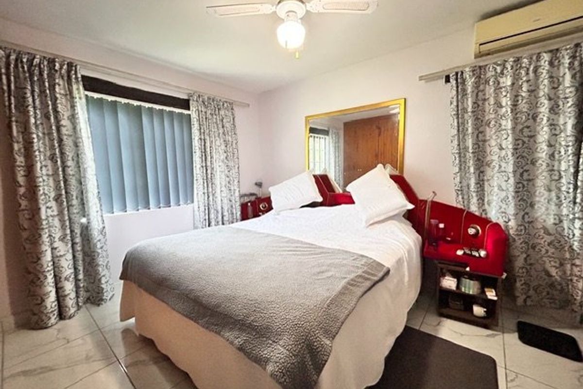A bedroom featuring tiled flooring, a ceiling fan, and a wall-mounted air conditioning unit.