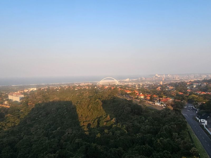 Elevated panoramic view overlooking the surrounding coastal landscape, urban infrastructure, and distant city skyline.