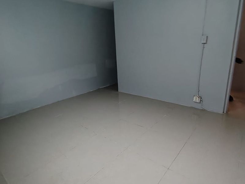 An empty, neutral-toned living area featuring tiled flooring and visible surface-mounted electrical wiring, offering a blank canvas for renovation or interior design.