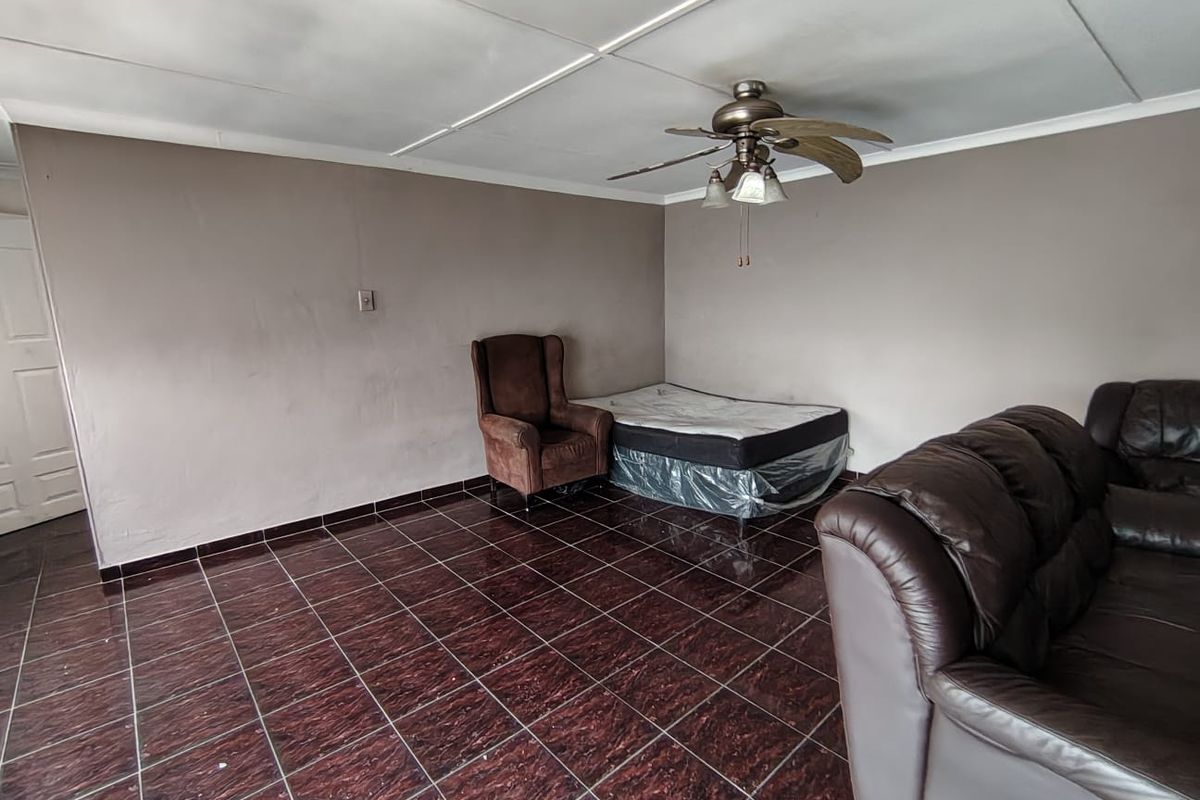 A bedroom featuring dark tiled flooring and a ceiling fan, requiring cosmetic updates to the ceiling and wall finishes.