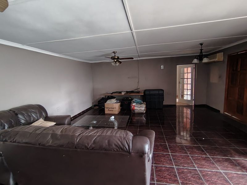 Spacious living area featuring dark tiled flooring, a ceiling fan, and access to an adjacent room through a classic french door.