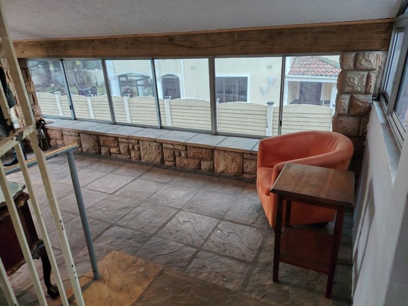 Enclosed patio area featuring stone cladding, tiled flooring, and large sliding glass windows overlooking the exterior.