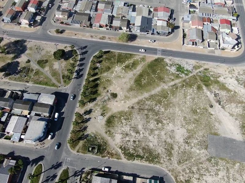 Aerial view of a vacant residential plot situated at a street corner, surrounded by established neighborhood infrastructure and paved roads.