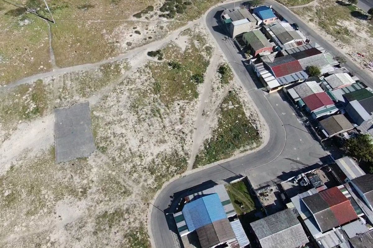 Aerial view of a vacant residential plot featuring a concrete slab, situated adjacent to an established residential street.