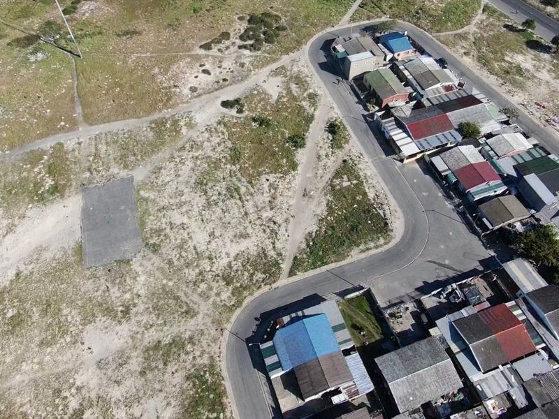 Aerial view of a vacant residential plot featuring a concrete slab, situated adjacent to an established residential street.