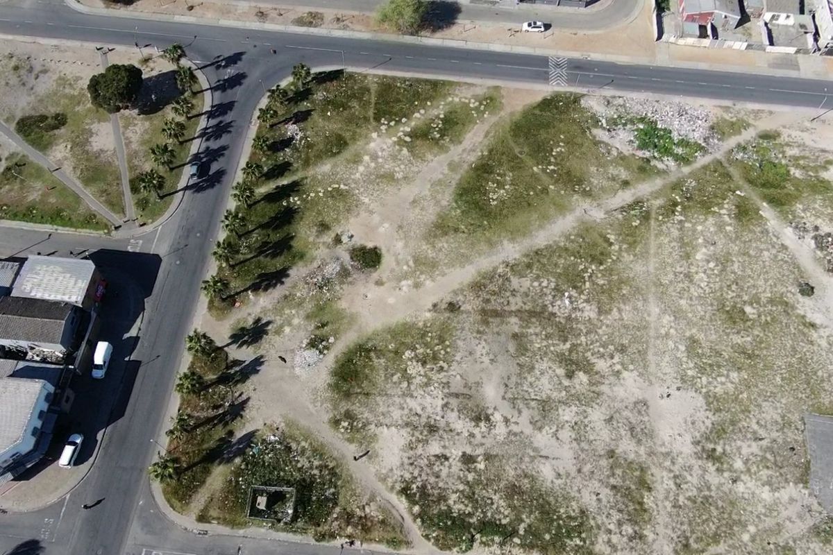 Aerial view of a vacant residential corner plot featuring established palm trees and direct access to surrounding paved roads.
