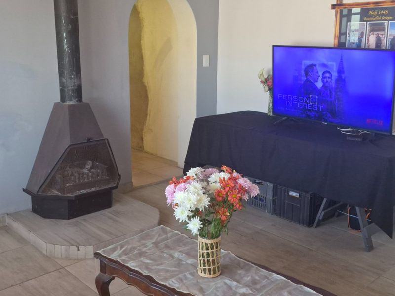 A living room featuring a freestanding fireplace, tiled flooring, and an arched doorway leading to an adjacent space.