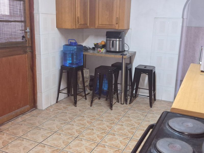 A functional kitchen featuring wooden cabinetry, tiled flooring, and a built-in electric stove with ample counter space.