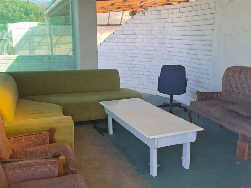 A covered outdoor patio area featuring painted brick walls and concrete flooring, offering a functional space for outdoor relaxation.