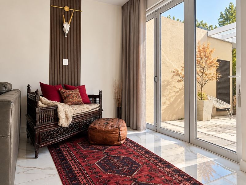 A bright living area featuring large glass sliding doors that open onto a patio, complemented by elegant marble-look flooring and decorative wood wall paneling.