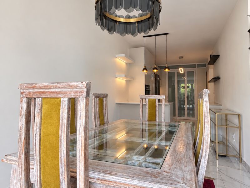 Modern open-plan dining and kitchen area featuring polished marble-look flooring, contemporary pendant lighting, and sleek built-in shelving with a clean, minimalist aesthetic.