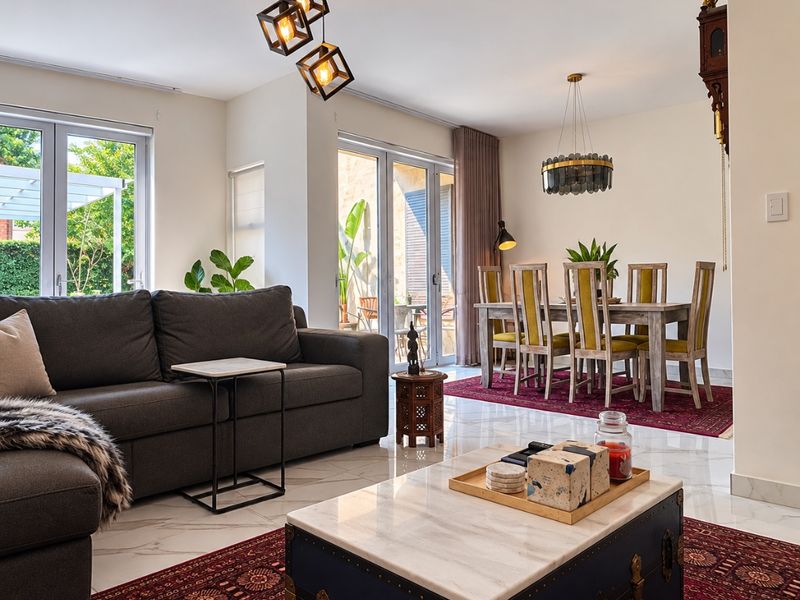 Spacious open-plan living and dining area featuring polished marble-look flooring, modern pendant lighting, and large glass sliding doors providing ample natural light.