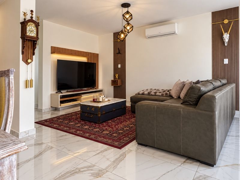 Modern living room featuring polished marble-look floor tiles, feature wall paneling, integrated media console, and split-system air conditioning.