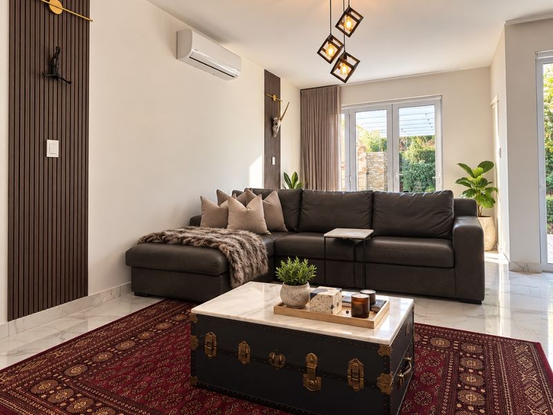 Modern living room featuring elegant slatted timber wall accents, polished marble flooring, split-system air conditioning, and direct access to the outdoor patio area.